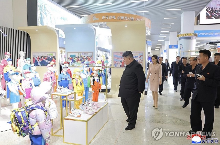 Kim Jong-un 2026 Ulusal Giyim ve Ayakkabı Sergisi'nde çocuk giysilerini inceliyor